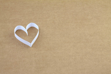 One white heart on a beige cardboard background with an empty place for your text. Valentine's day stock photo for web, print, postcards, invitations, wallpaper and background.