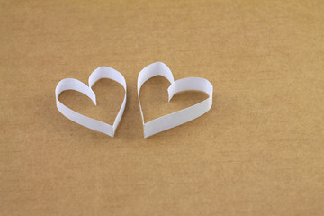 A pair of white hearts on a beige cardboard background with an empty place for your text....
