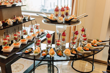 Delicious Snacks Assortment on Table Photography. Seafood Shrimps and Fish Meat with Green Leaves Parsley on Spoon and Snacks on Stick Strawberry with Cheese and Tomato with Mozzarella in Glasses