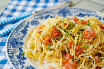 Pasta primavera with grilled shrimps on blue plate close up