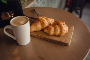 Cappuccino with beautiful latte art and croissant on wooden background