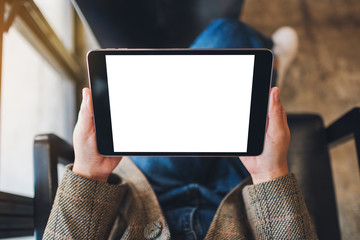 Top view mockup image of a woman sitting and holding black tablet pc with blank white desktop screen