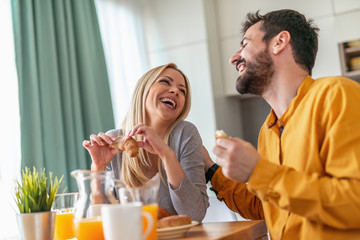 Cheerful couple having breakfast at home