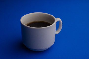 A cup of fresh coffee on blue background with text space. Flat lay. Top view. Minimalism