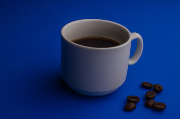 Cup of Coffee espresso with coffee beans on blue background. Flat lay, creative design.