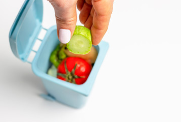 Female hand throws food garbage in trash can on white background.