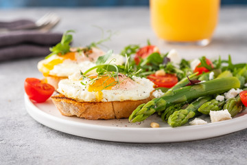 Fototapeta na wymiar Egg and green asparagus on toast with greens. Healthy breakfast.