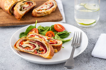 Italian food Pizza roll stromboli with cheese, salami, spinach and red pepper a light background.