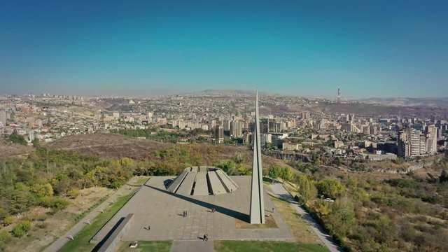 Aerial drone zoom in shot of Tsitsernakaberd museum on background of city panorama in summer in Yerevan, Armenia. Drone shot of Yerevan museum with city panorama view