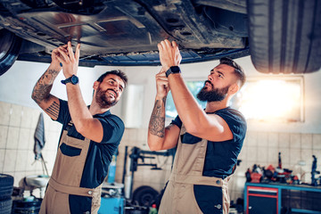 Two mechanics repairing car in service center
