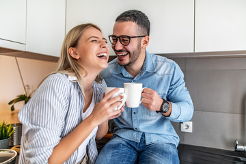 Cute young couple drinking coffee in kitchen