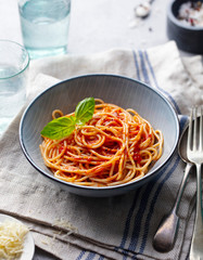 Pasta, spaghetti with tomato sauce and fresh basil in a bowl. Grey background.