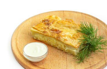 This is baked pastry in layers with feta cheese on a wooden board.