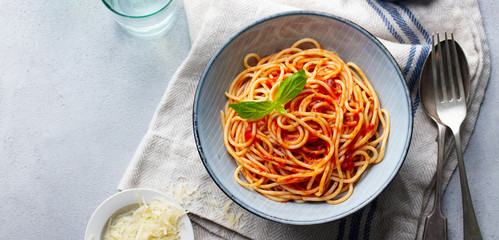 Pasta, spaghetti with tomato sauce and fresh basil in a bowl. Grey background. Top view. Copy space. - obrazy, fototapety, plakaty