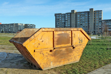 Orange steel container for construction and industrial waste installed in a residential area of the...