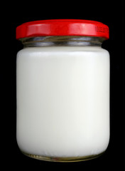 Small one hundred gram glass jar with white milk and a red lid isolated black macro