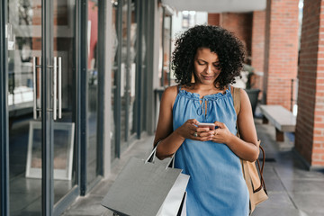 Smiling woman using her cellphone while out shopping