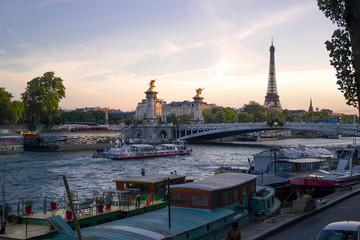 Obraz premium Beautiful sunset over the river Seine. Sailing pleasure boats with tourists, the Pont Alexandre III and the Eiffel Tower in the background.