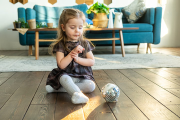 Little cute toddler girl playing with a ball in modern home in Scandinavian style interior