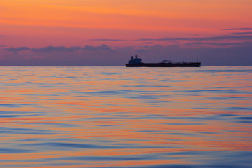 Amazing pink colors during sunset in the middle of Atlantic Ocean and view of Tanker ship passing.