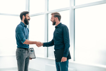 financial pratners shaking hands while standing in the office.