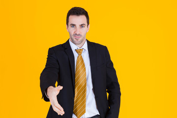 Business man wearing blacksuit Reach out hand for handshake on orange yellow background.