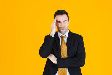 Business man wearing blacksuit have a headache sign on orange yellow background.