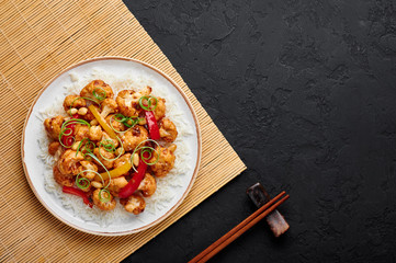 Kung Pao Cauliflower at dark slate background. Sichuan Kung Pao Cauliflower is chinese cuisine vegetarian dish with chilli peppers, peanuts, sauces and onion. Copy space. Top view