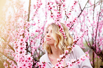 Portrait of beautiful pregnant woman posing against the pink flower trees gardenand fog in spring,...