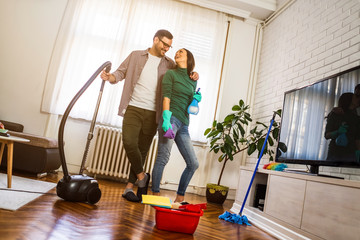Young happy couple is cleaning their apartment.
