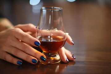 Woman hand holds a glass of whisky