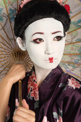 Close-up of Japanese woman with painted face holding parasol