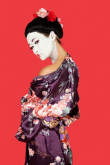 Portrait of Japanese woman in kimono standing over red background