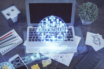 Double exposure of blockchain theme hologram and table with computer background. Concept of bitcoin crypto currency.