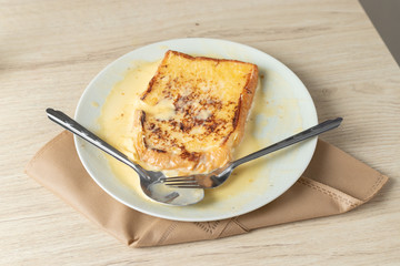 Toast on a white plate on a wooden table.