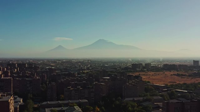 Aerial drone shot of fields and car road on background of Ararat mountains in summer time during sunset. Dron shot of sunset flying over Yerevan