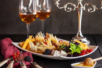 slicing different cheeses in a plate with a glass of wine on the table