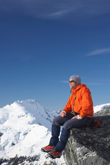 Mountain climber sitting on edge of mountain peak