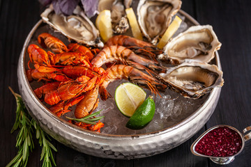 A large plate with seafood on ice. Crayfish, Shrimp and Oysters