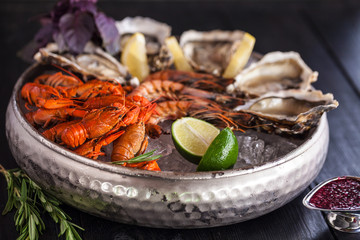 A large plate with seafood on ice. Crayfish, Shrimp and Oysters