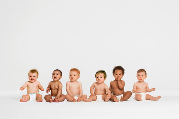 A group of mult ethnic babies sitting in a studio