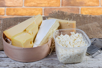 Different varieties of cheese and cottage cheese on wooden surface