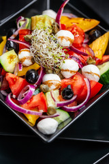 salad with tomato, cucumber, olives, bell pepper, onions and baby mozzarella in a plate