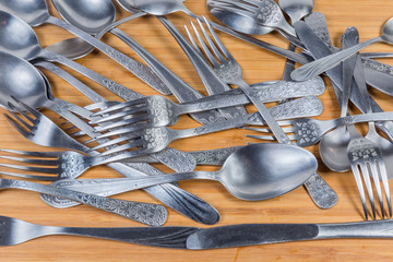 Background of various stainless steel eating utensils on wooden surface