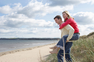 Man giving woman piggy back at beach