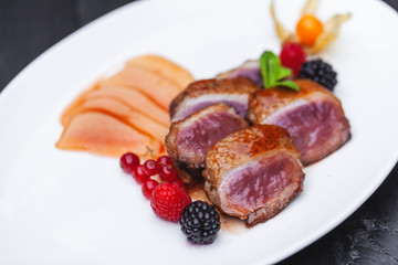 pink duck breast with berry sauce, physalis and pear