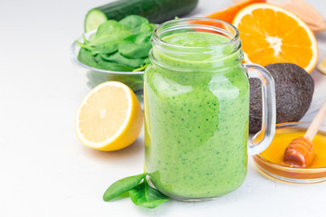 Green detox smoothie with avocado, spinach, cucumber, orange, lemon and honey, in glass jar, horizontal, copy space, closeup