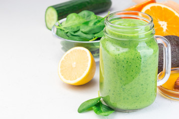 Green detox smoothie with avocado, spinach, cucumber, orange, lemon and honey, in glass jar, horizontal, copy space