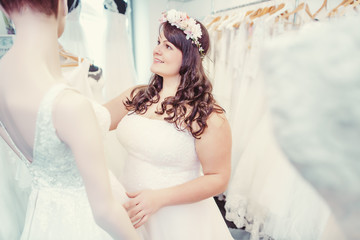 Woman as bride to be looking for bridal wear in a wedding shop