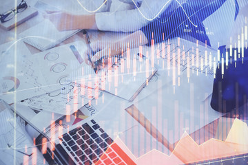 A woman hands writing information about stock market in notepad. Forex chart holograms in front. Concept of research. Double exposure